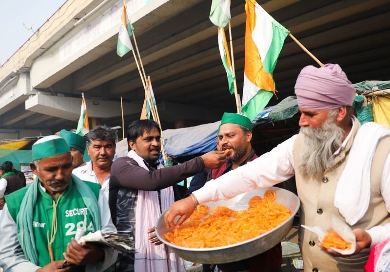 Farmers feed each other sweets and celebrate after PM Modi announced that he will repeal the controversial farm laws.